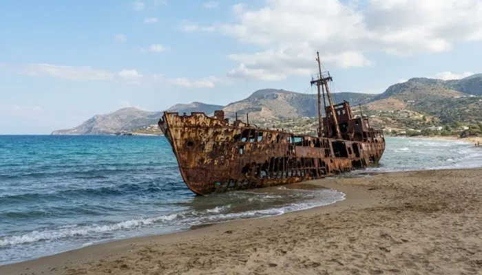 The skeletal and rusty frame of the Dimitrios shipwreck beached on the sandy coast of Gytheio, Greece.