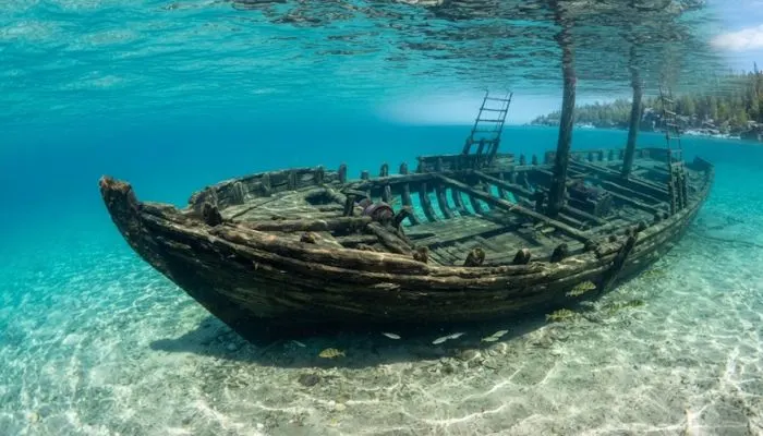 Clear turquoise water showing the submerged wooden frame of the Sweepstakes schooner shipwreck in Lake Huron, Canada.